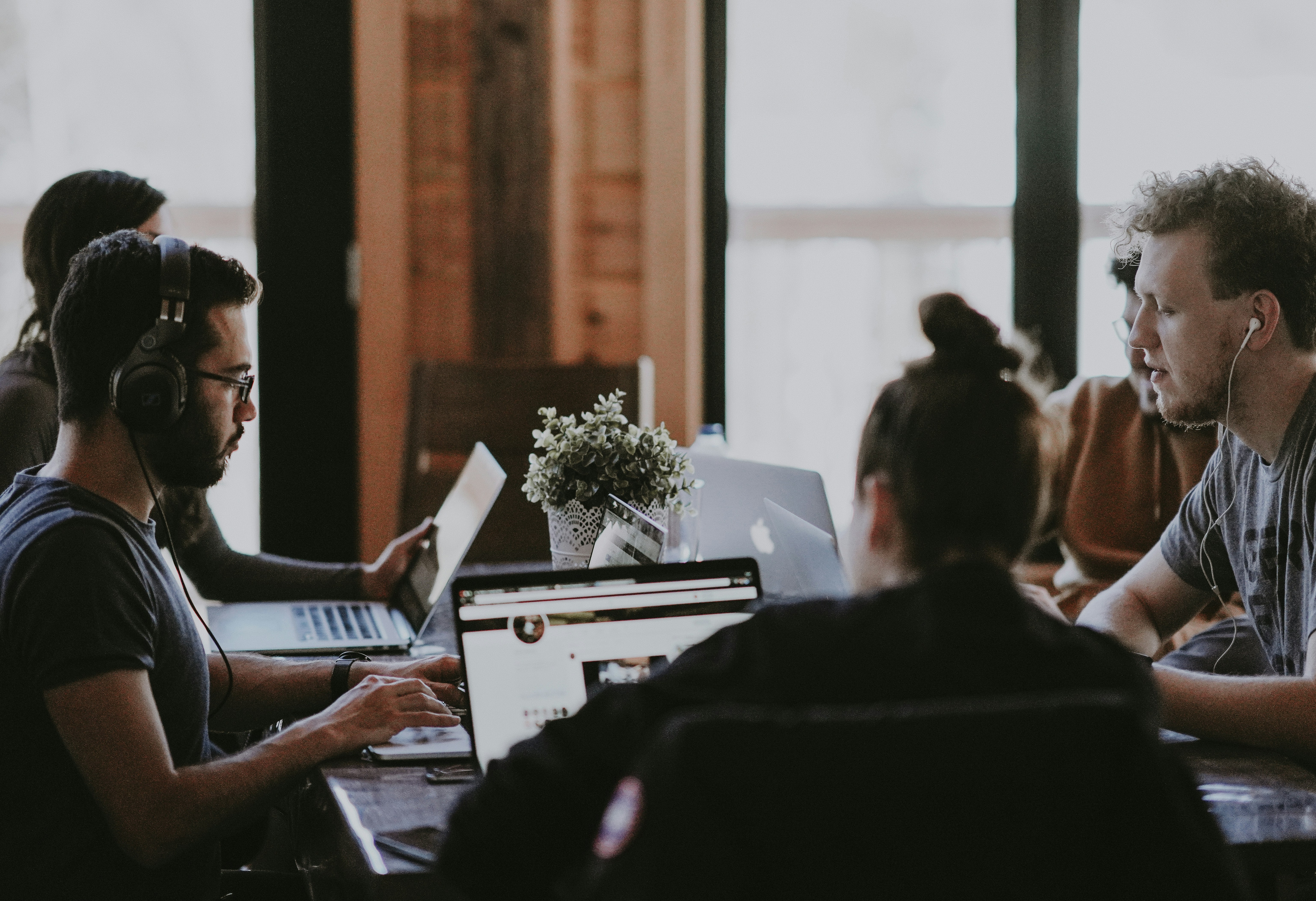 Mitarbeiter in einem modernen Büro, die an Computern arbeiten und in kleinen Gruppen diskutieren, offene Bürogestaltung mit kreativen Elementen