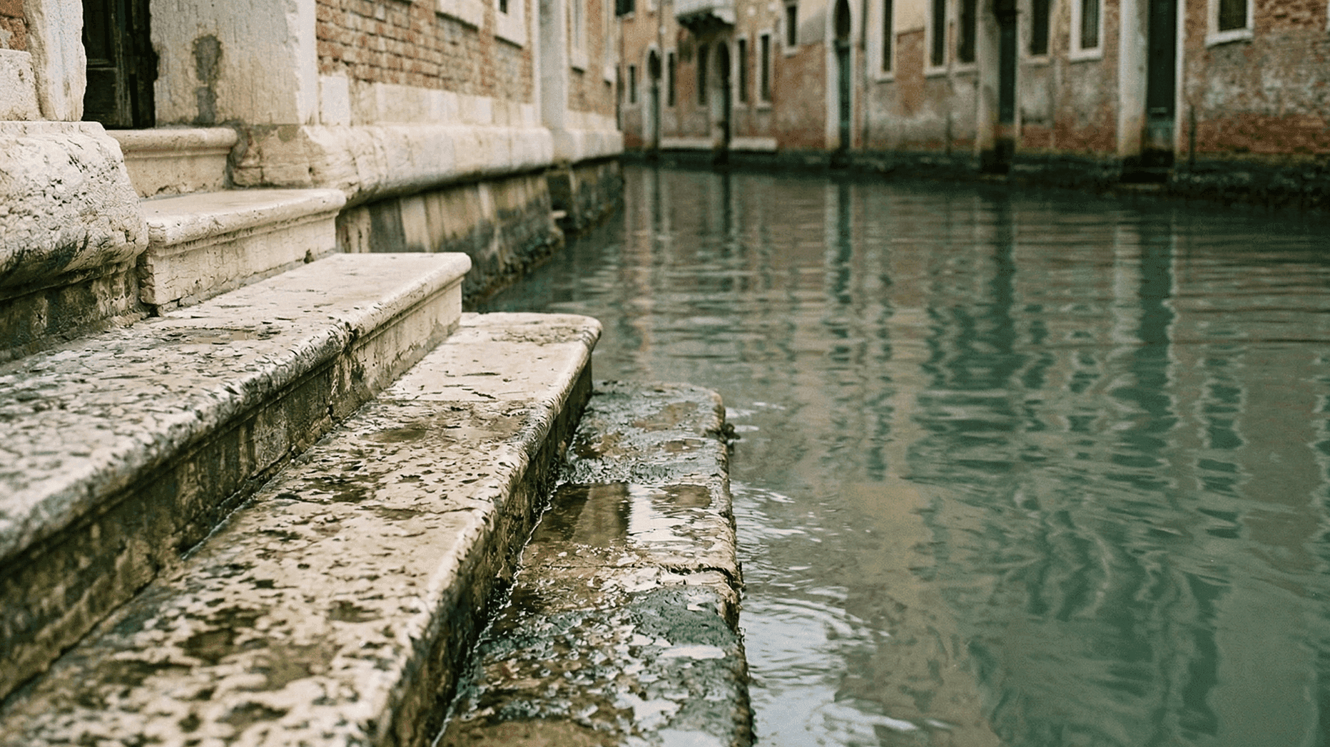 Старые каменные ступени у воды на тихом канале Венеции