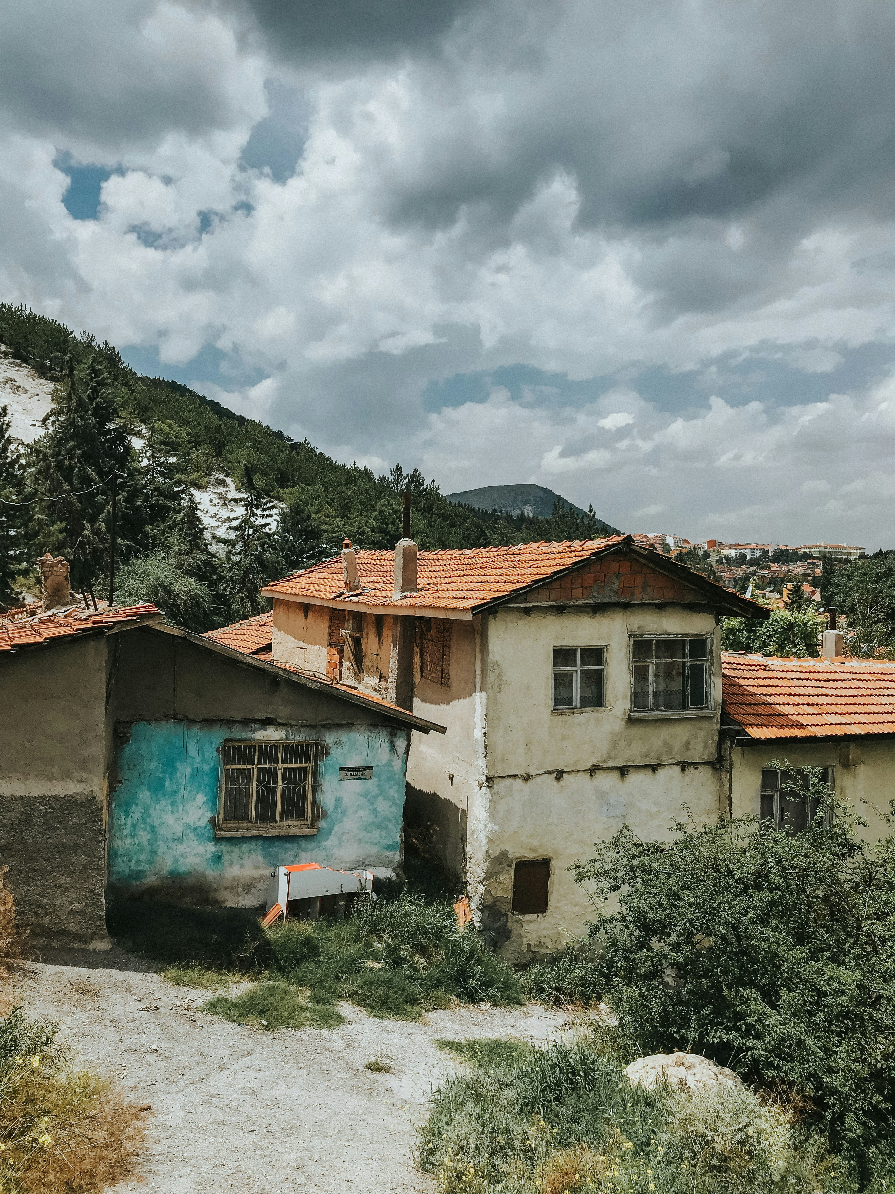 white and brown concrete house near green trees under white clouds during daytime
