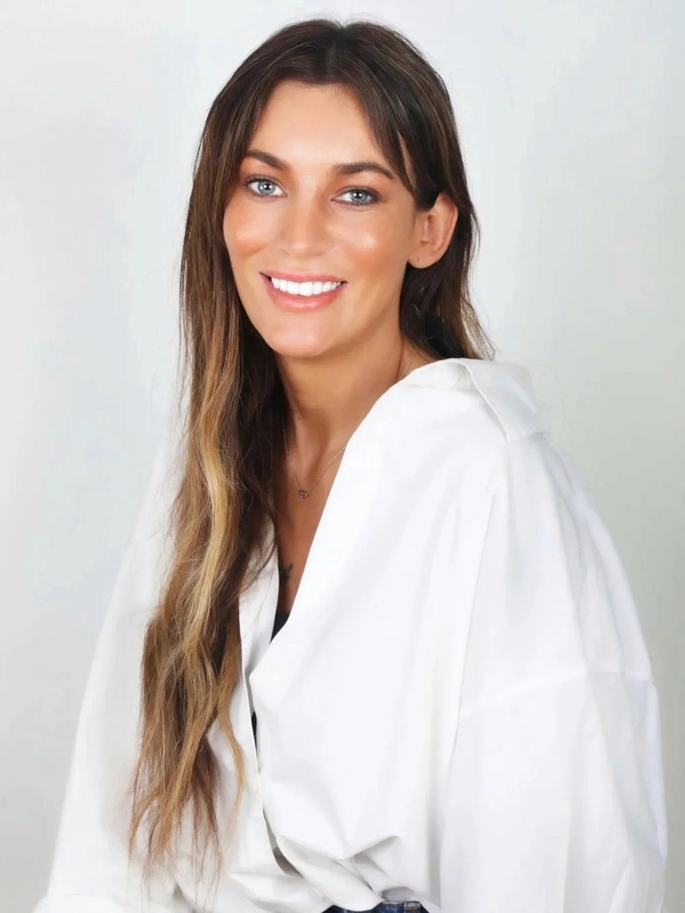 A photo of Dr Sarah Jane, founder of Spinal Energetics. She has long dark hair and blue eyes, wearing a white top