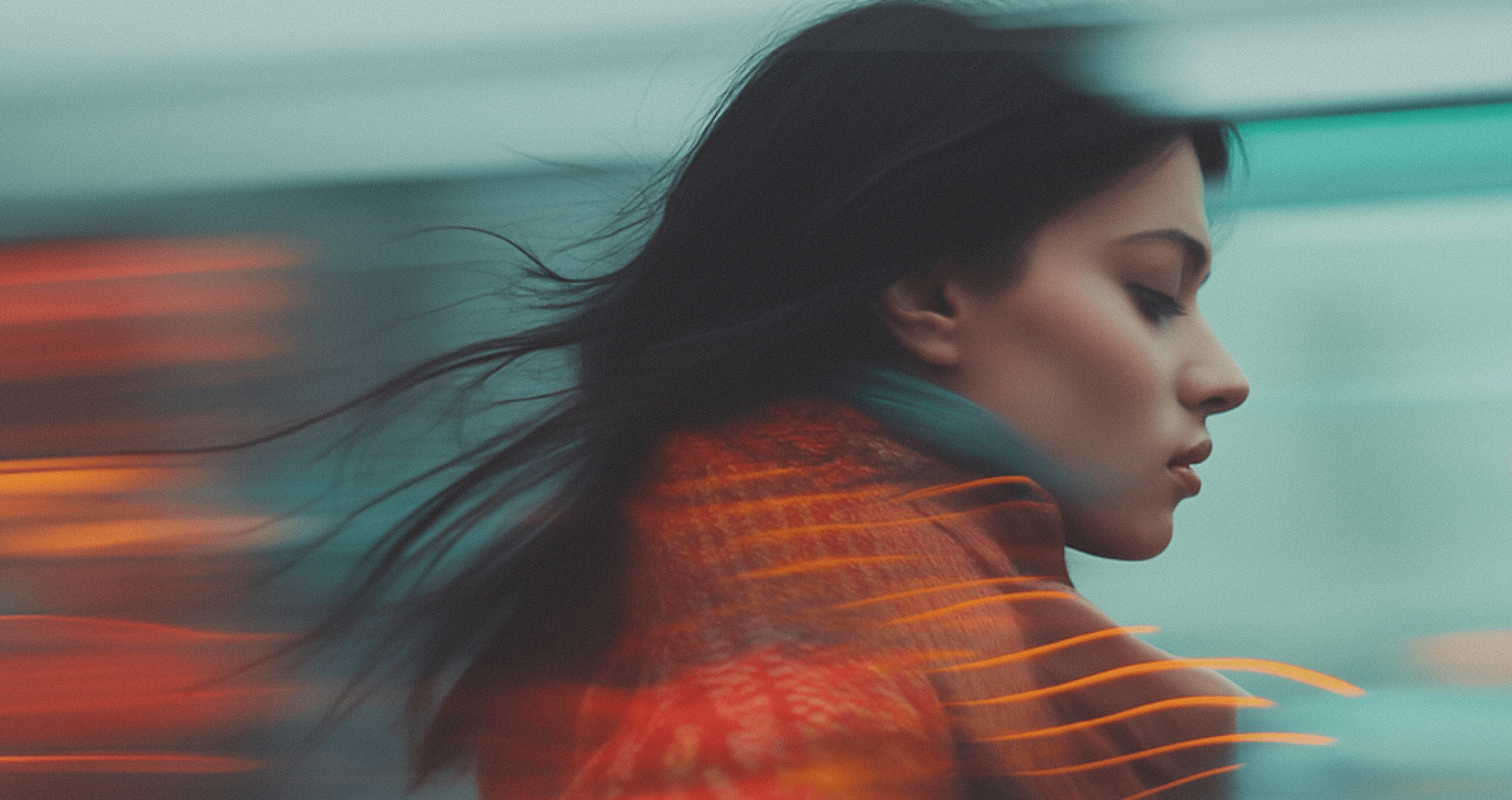 Artistic motion blur portrait of a woman in red coat with flowing hair at night