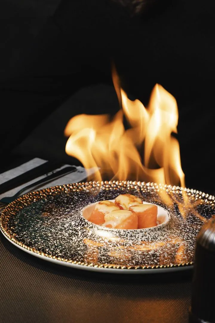 Flambéed salmon served on a glittering plate, a Sushi Club signature dish