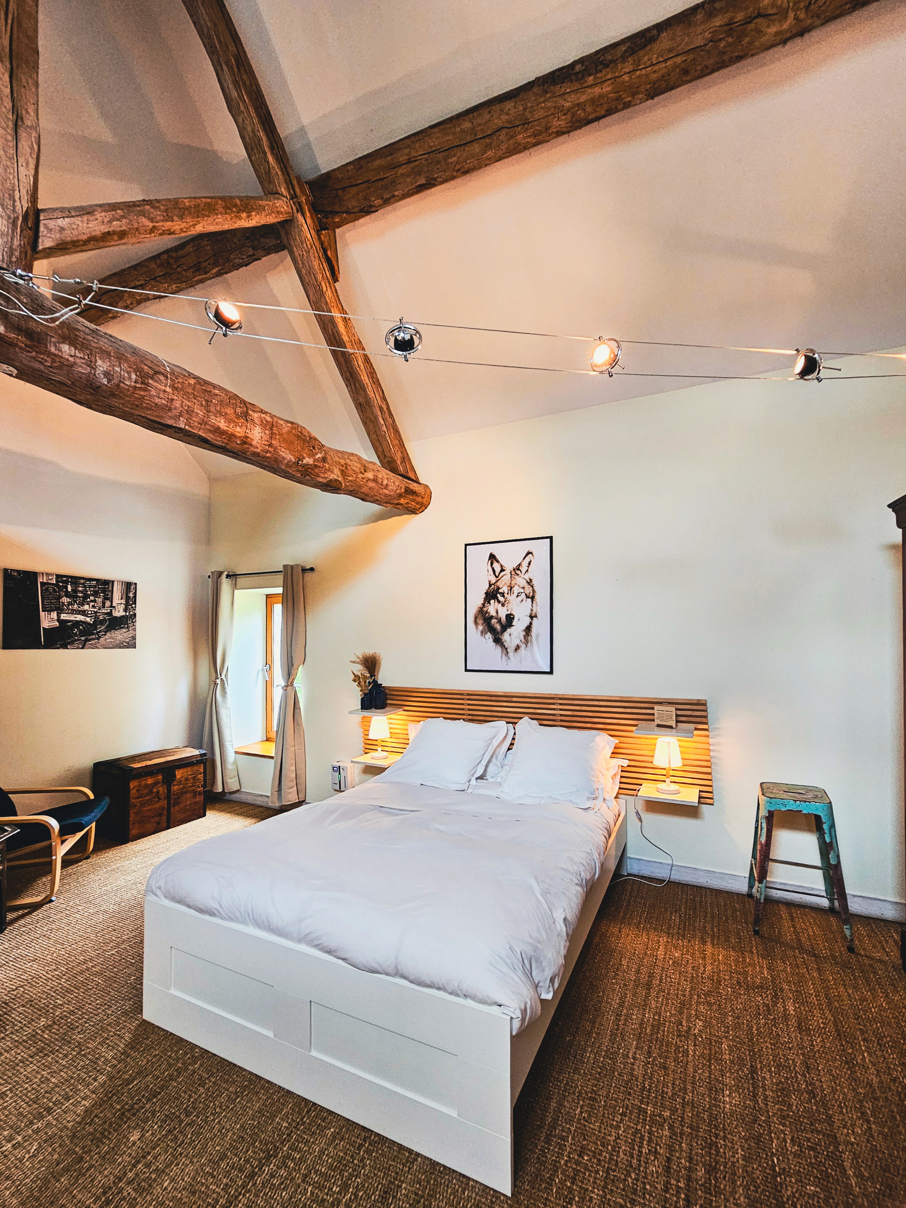 Chambre avec lit double et poutres apparentes.