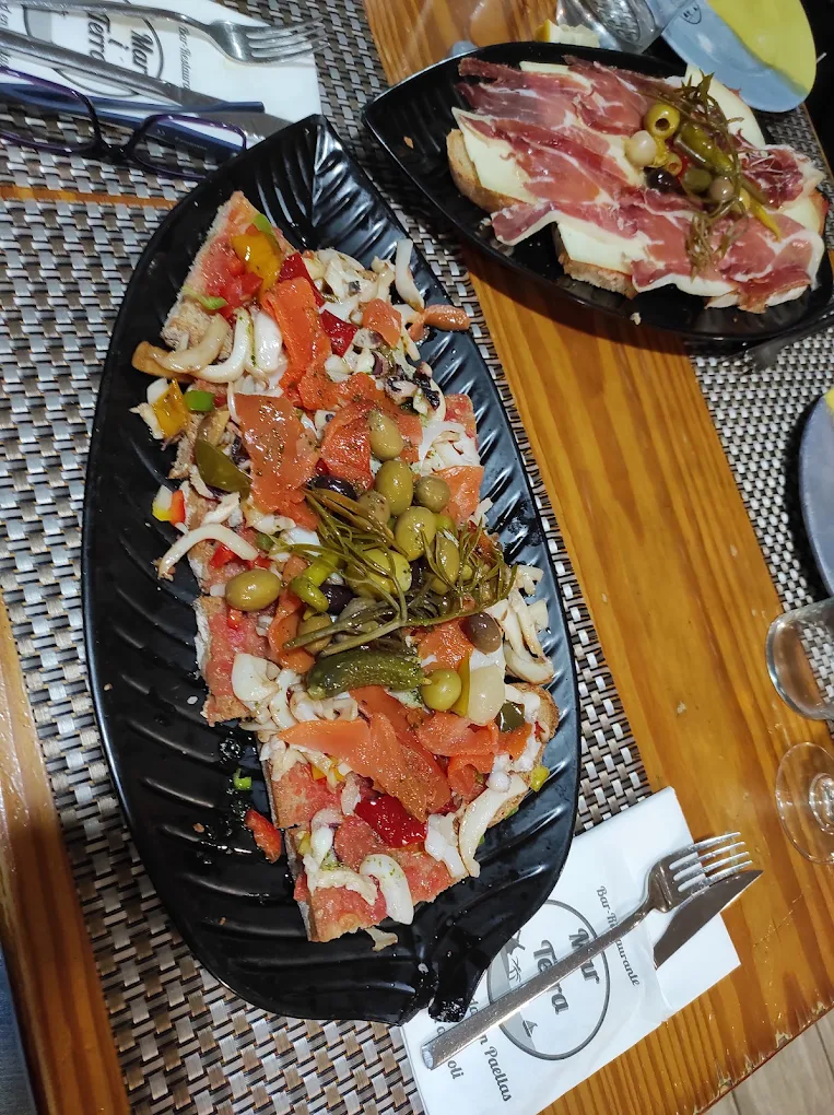 Dos variedades de pa amb oli de Mar i Terra en Son Ferriol con queso, embutidos, aceitunas y guindillas.