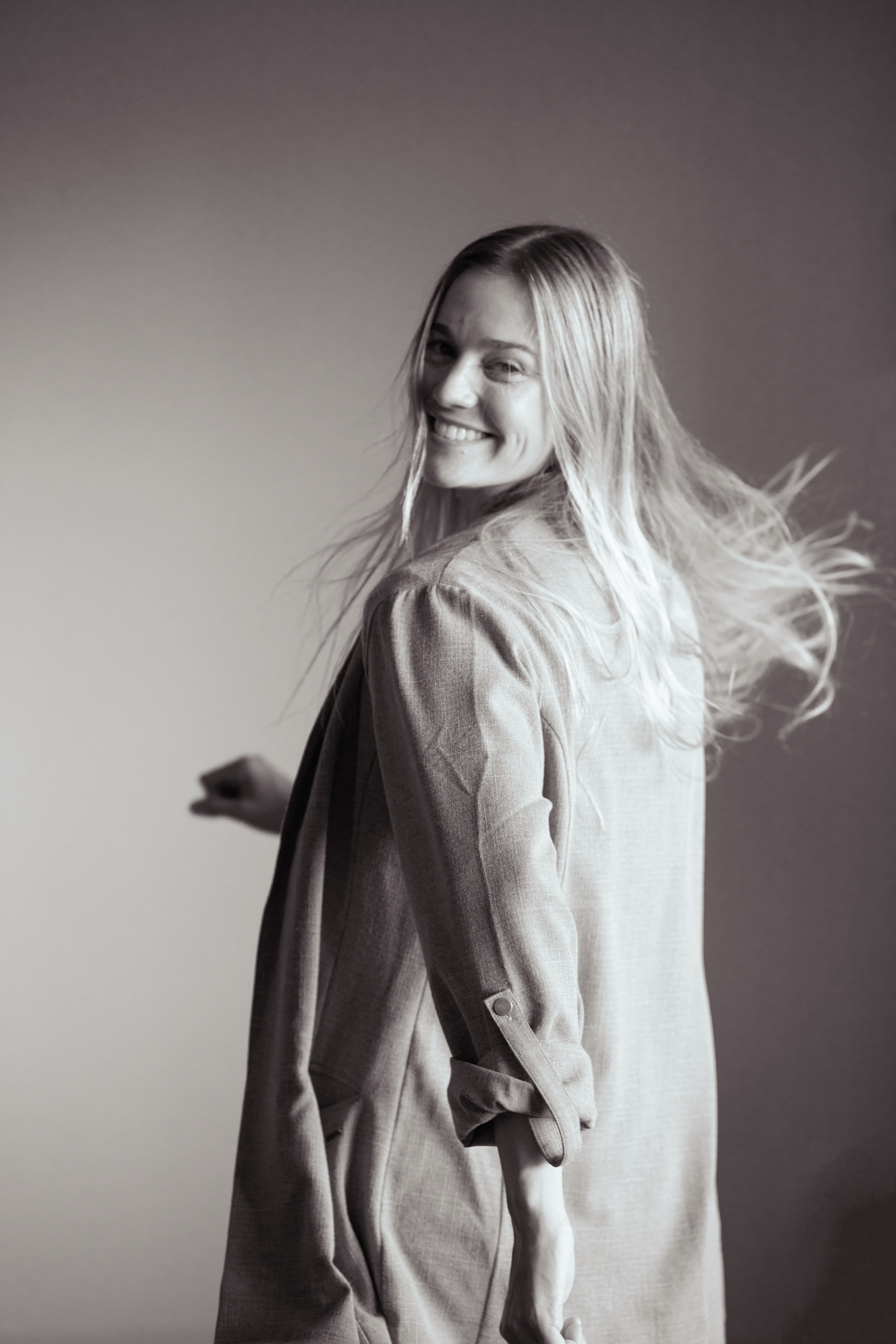 A thoughtful young person with dark hair gazes to the side, captured in soft black and white lighting.