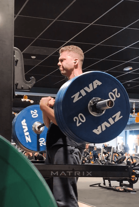 Full body portrait of athletic shirtless male doing biceps workouts with dumbbells in a gym club.