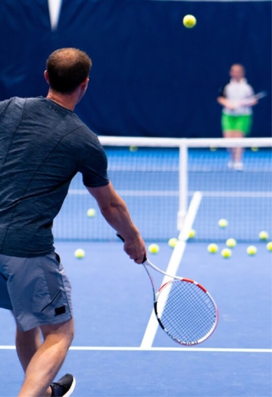 A man and a woman playing tennis outside in a tennis court.
