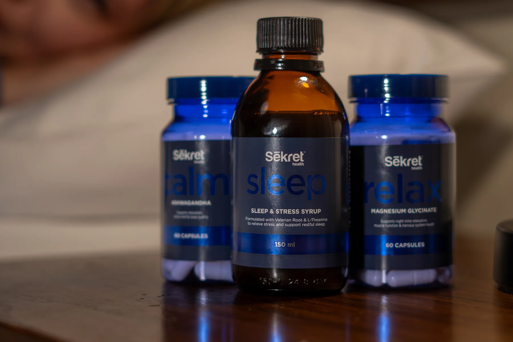 Sekret Calm, Sleep and Relax standing together on a bedside table in low evening light
