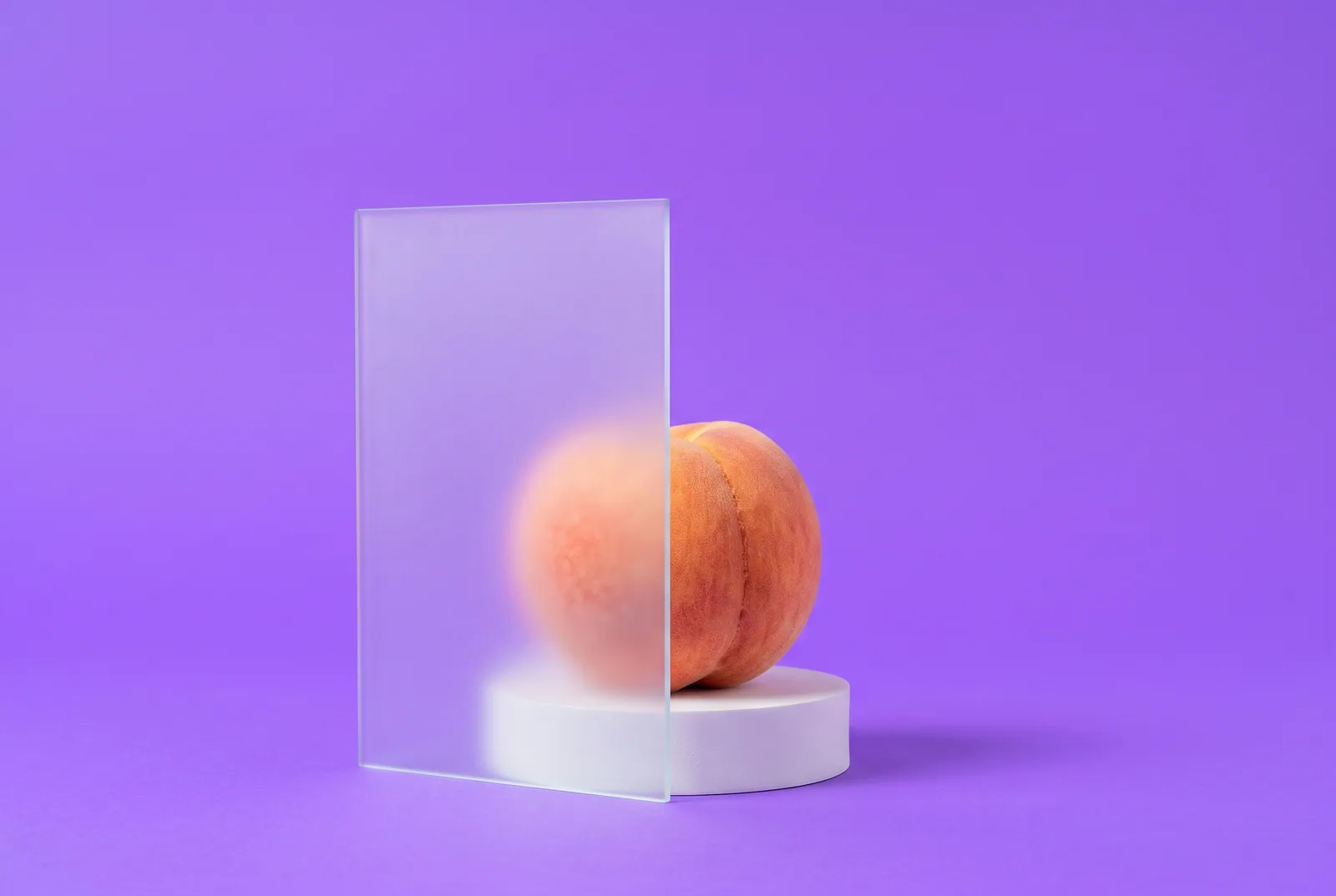 Ripe peach seen through a pane of frosted glass on a lilac backdrop, a visual metaphor for how to block NSFW on Reddit