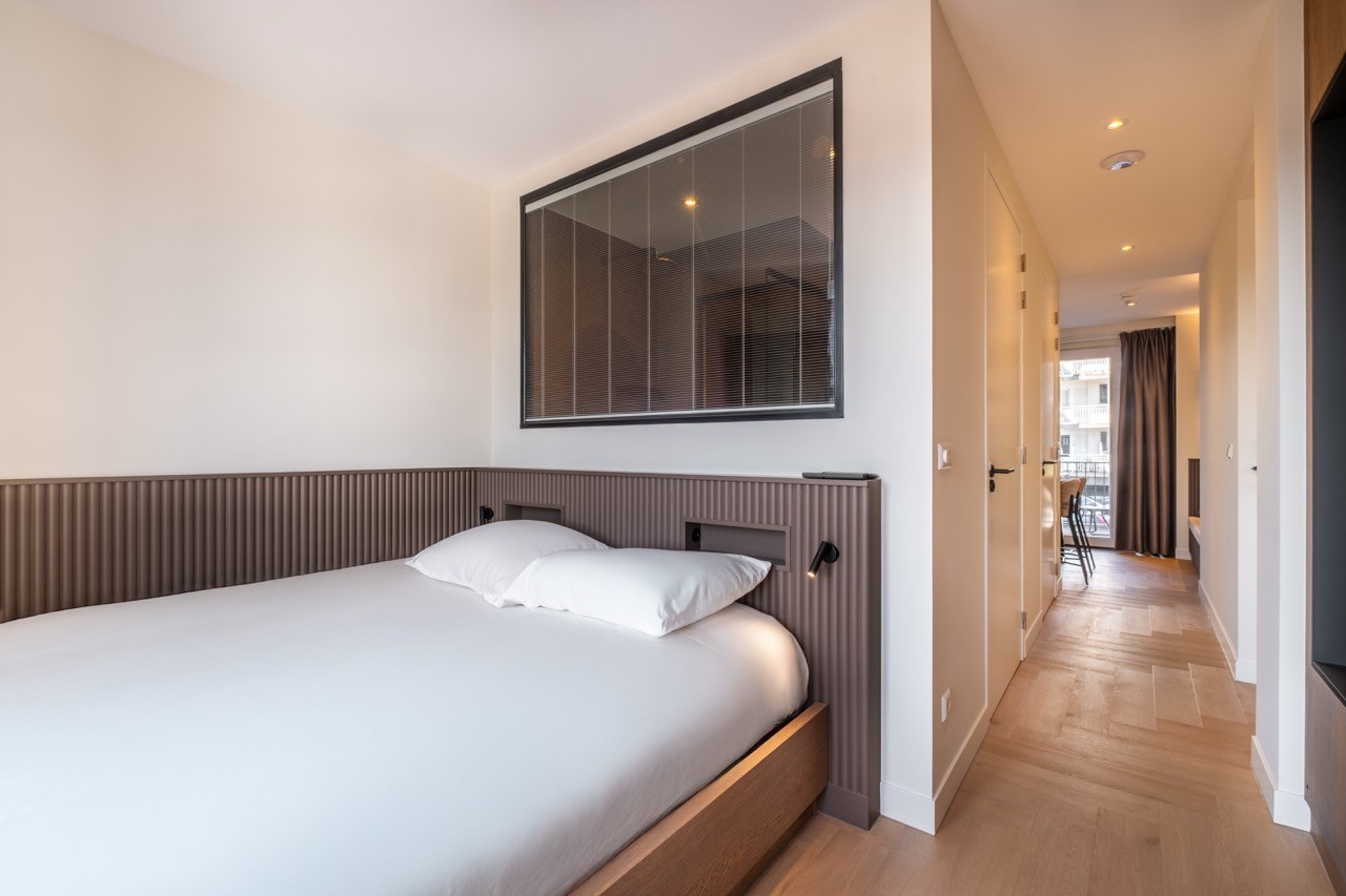 Moderne suite met tweepersoonsbed en zicht op gang in Hotel Four Stories