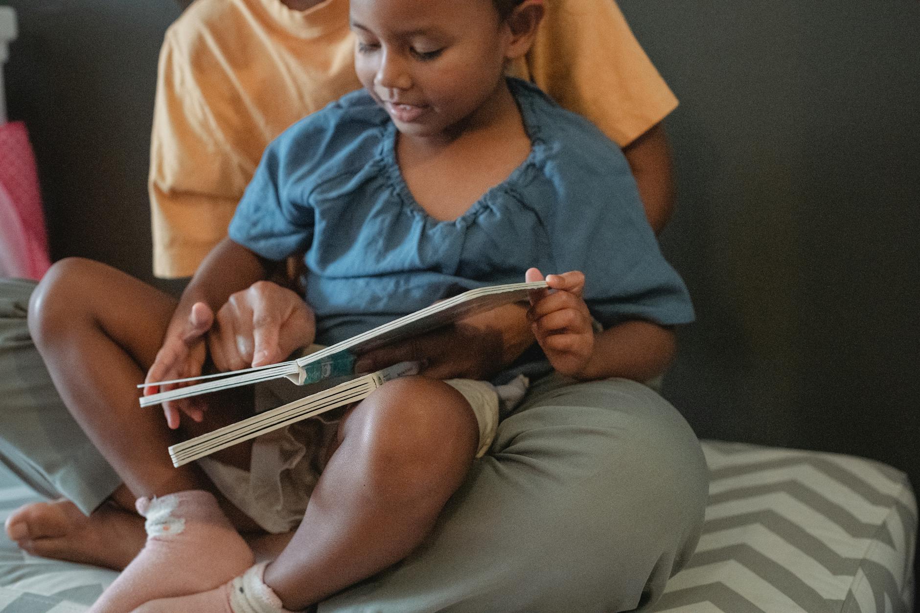 A father and daughter sitting in a cozy reading nook selecting pre reader books from a low wooden bookshelf.