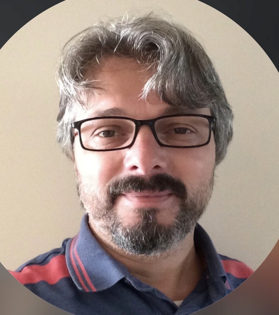 Minimal studio portrait of a confident woman in a white shirt, arms crossed, on a soft gray background.
