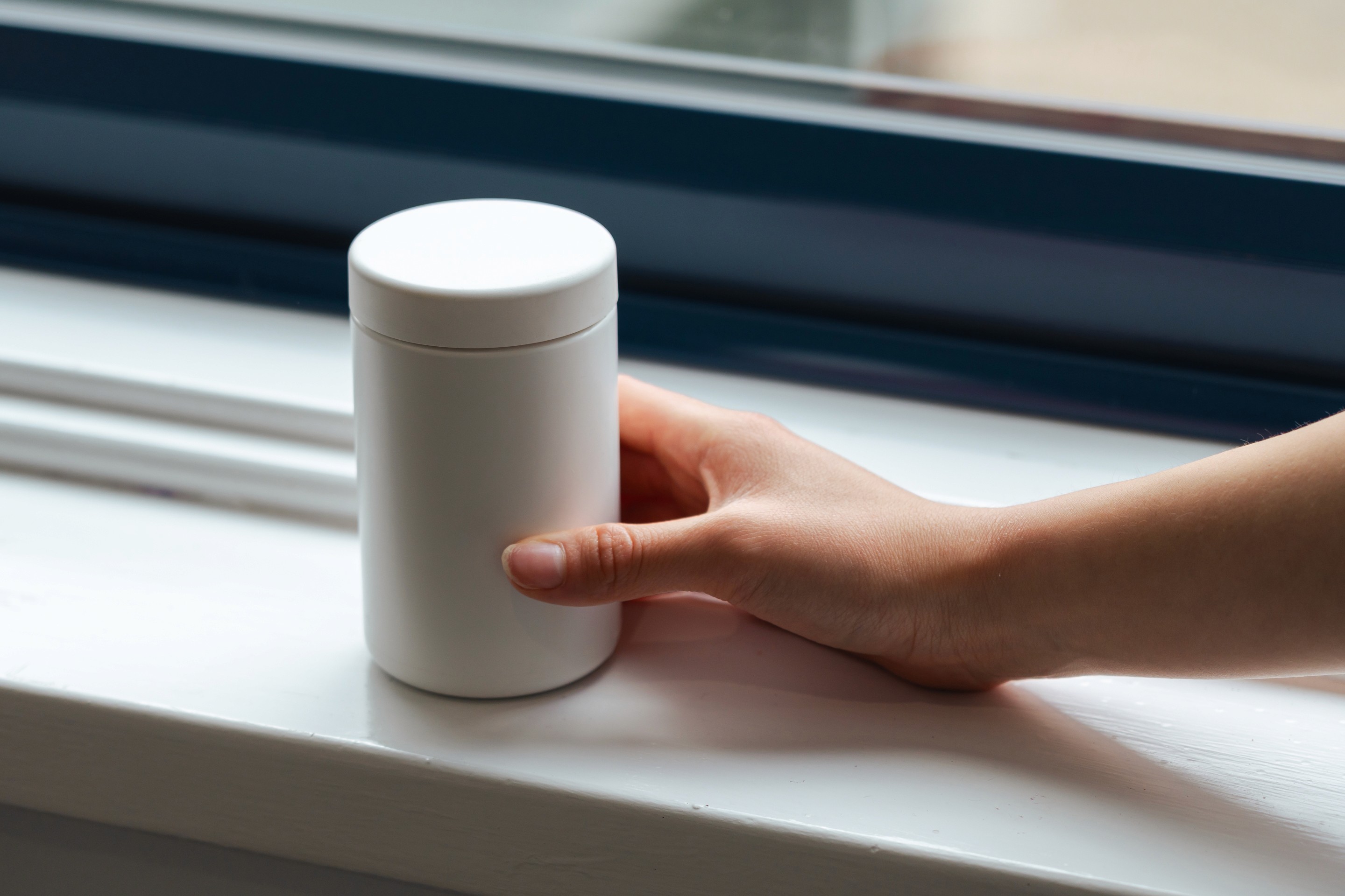 A model holding a closed 400ml VIVOMER supplement bottle. The rigid and secure container provides a petroleum-free alternative for large volume health and wellness products.