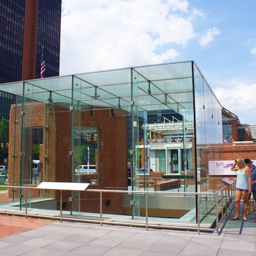 一个玻璃封闭结构，里面有砖墙、信息面板，两个人正在查看一个大型户外展示。