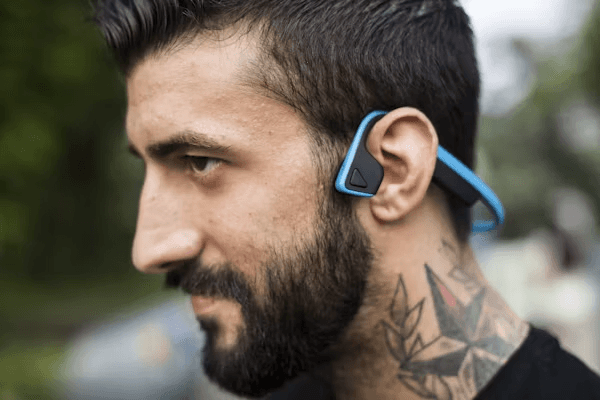 A runner outdoors wearing open-ear headphones
