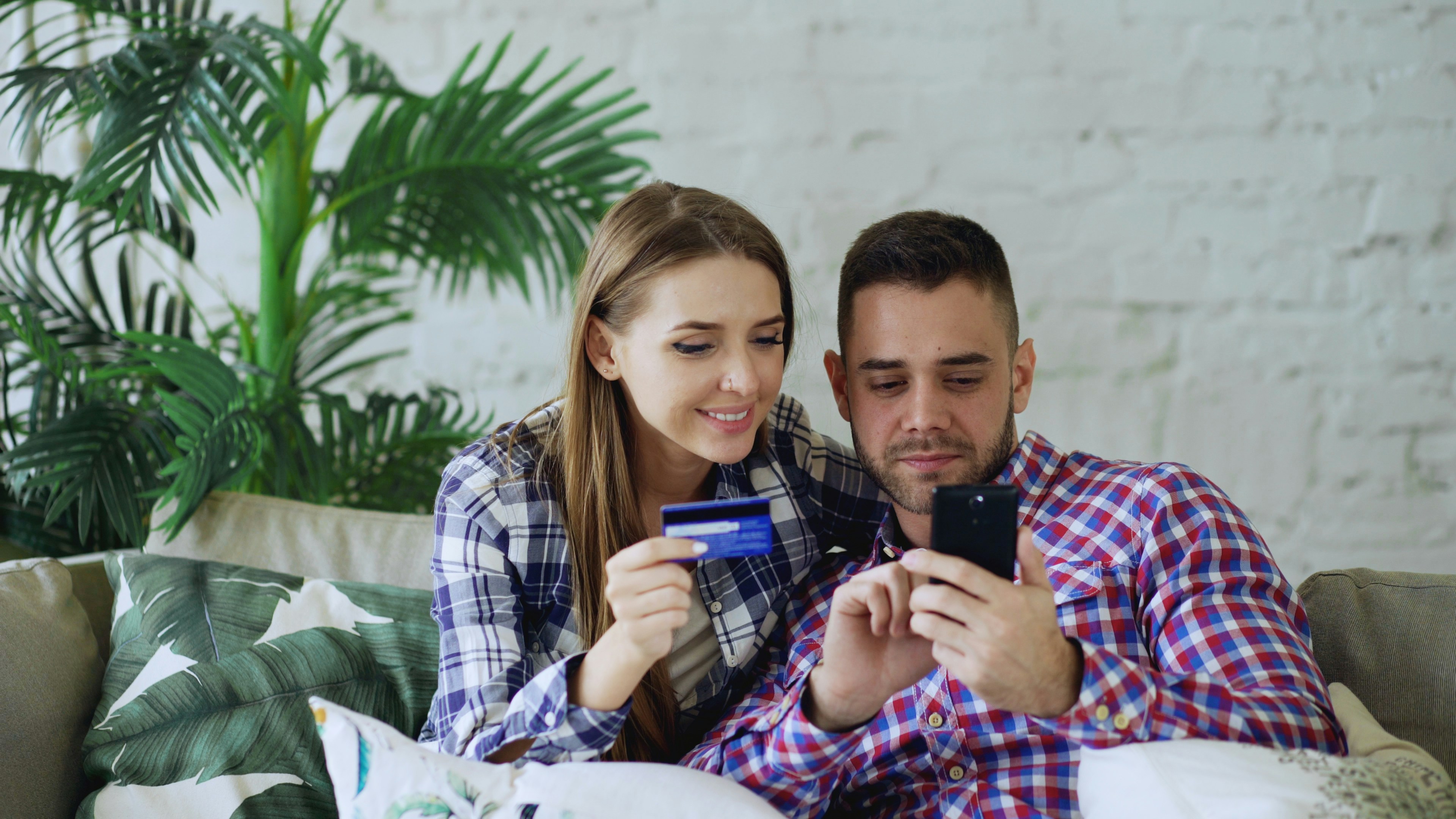Couple happily shopping online with credit card and phone.