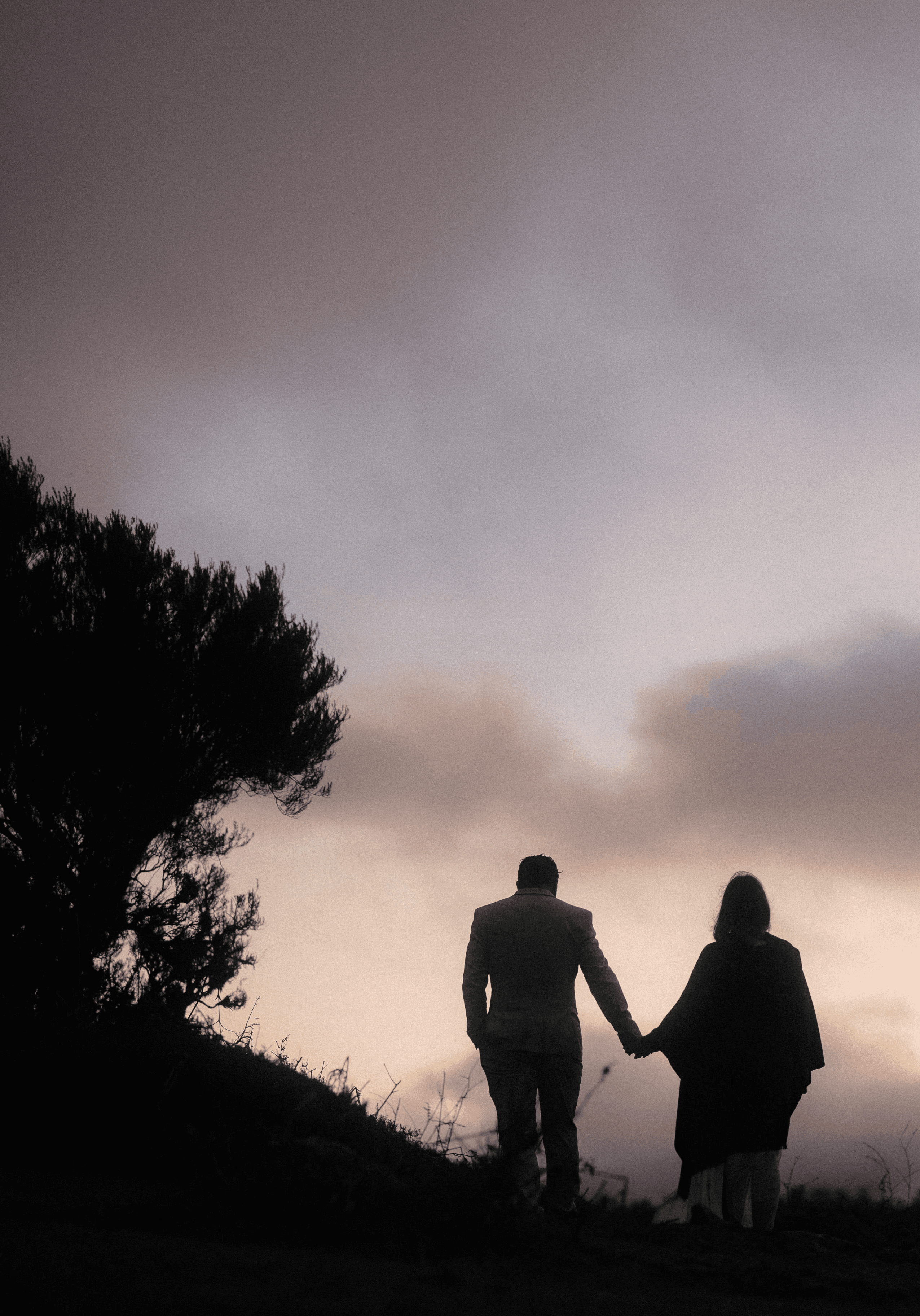 silhouette on painted sky of couple walking hand in hand