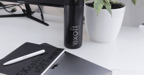 A silhouetted astronaut stands before a glowing portal in a misty, green-lit environment, with their reflection visible in a puddle.