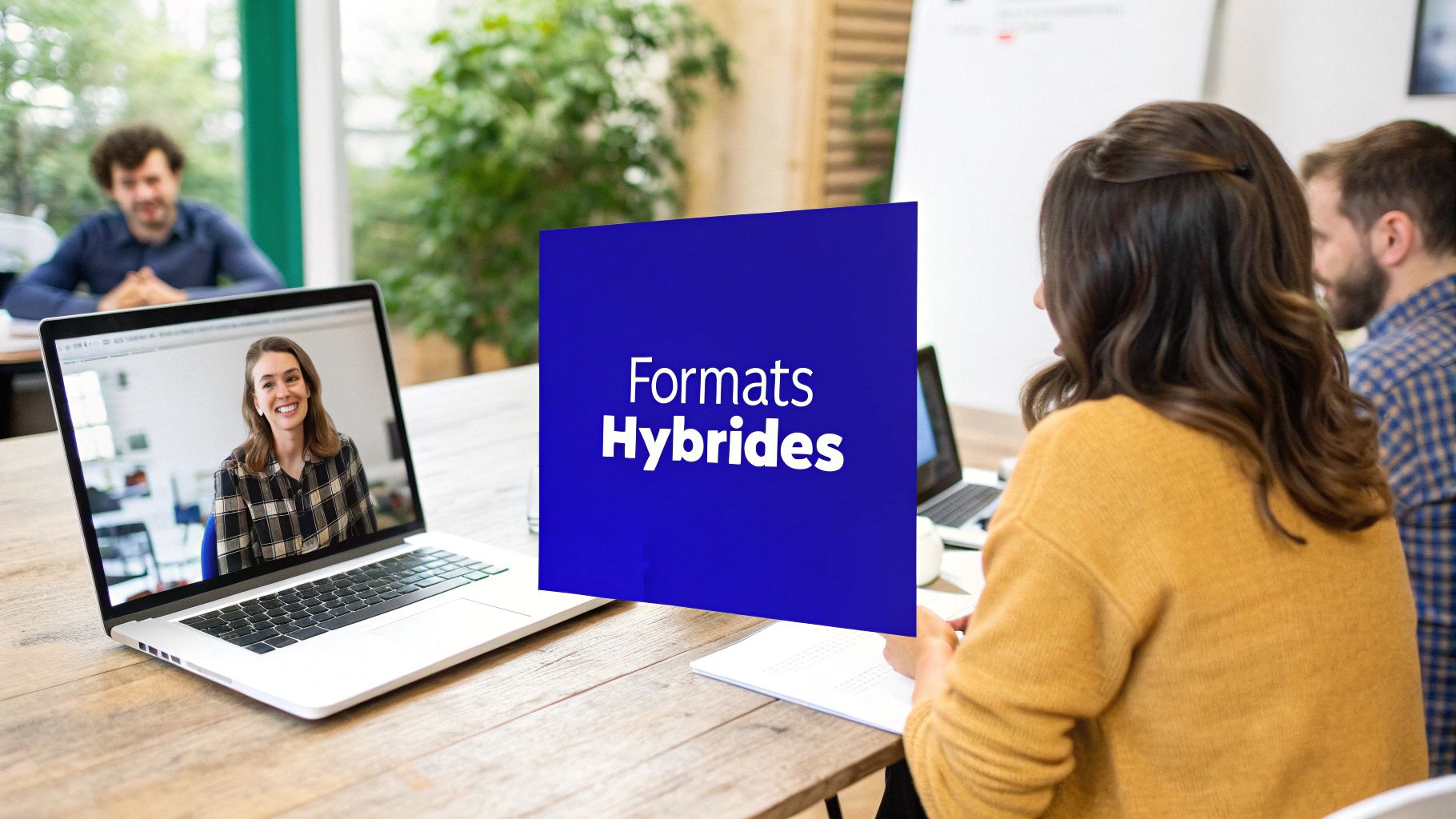 Des professionnels participent à une réunion hybride avec une personne à distance sur un ordinateur portable, et une enseigne 