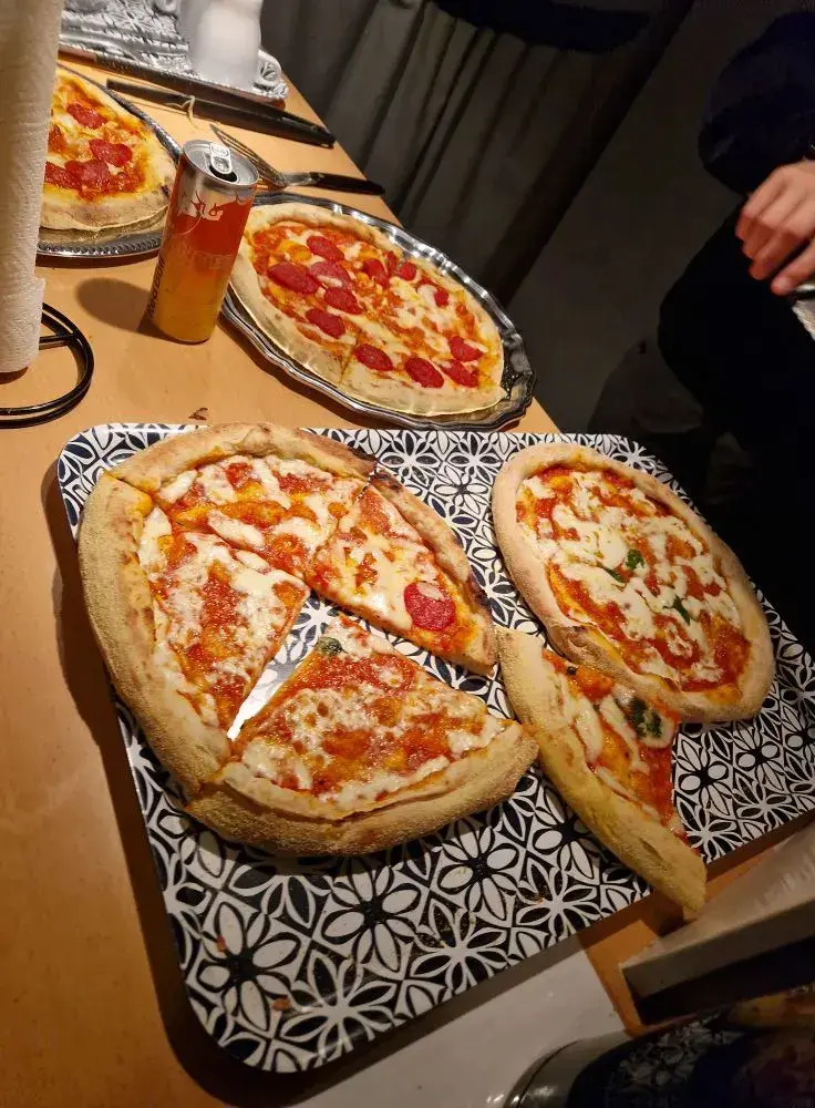 Pizza uppdukad på bord som delas under en gemensam måltid.
