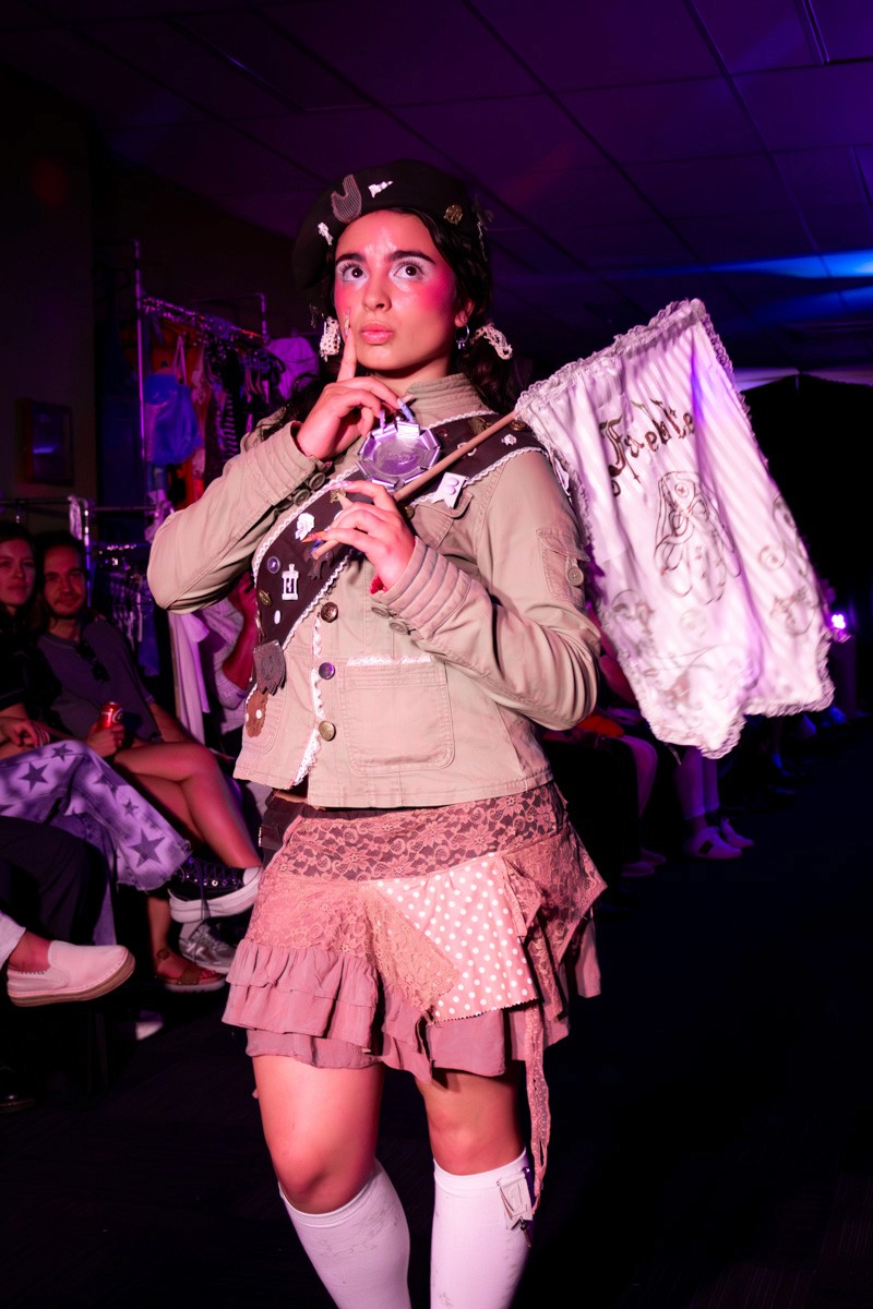 female model on runway wearing girl scout style clothes and waving a flag