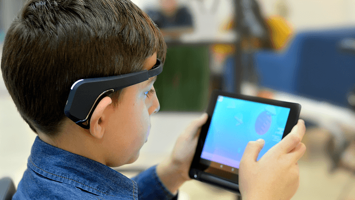 Real-Time Tracking: A boy wears a training headband  while playing   a game on the Myndlift app at the clinic,  allowing continuous monitoring   of his brain activity.