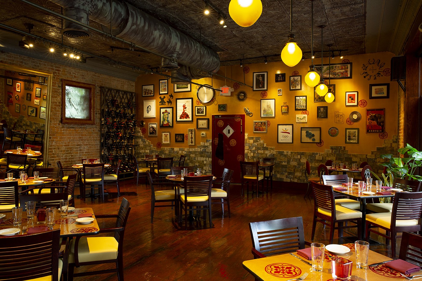 Dining room with yellow pendant lights, framed art on the walls and set tables at Barcelona Restaurant