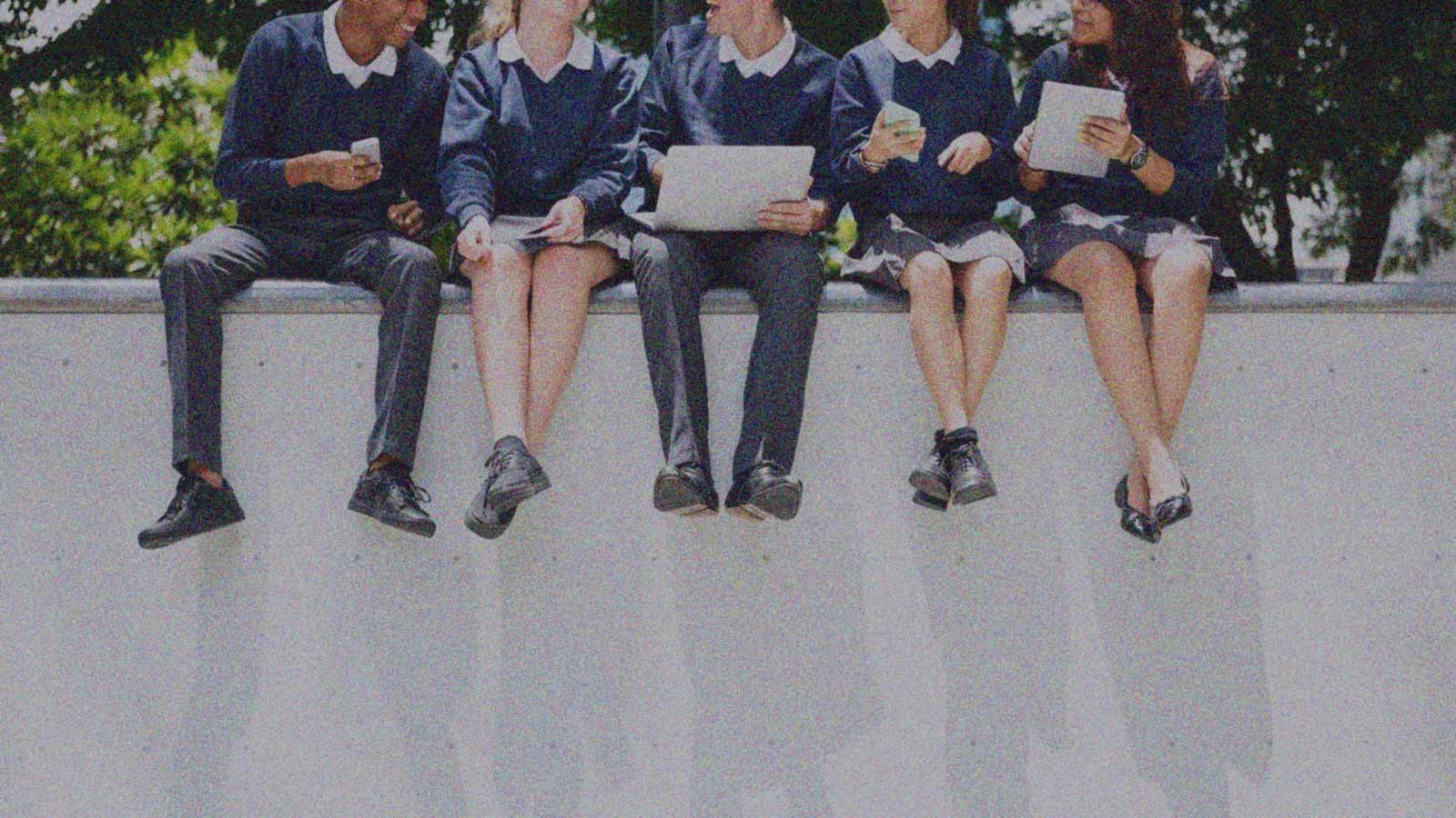 Foto que muestra las piernas de jóvenes que están sentado en un muro en la columna de opinión ¿Dónde está el efecto par? de IdeaPaís.