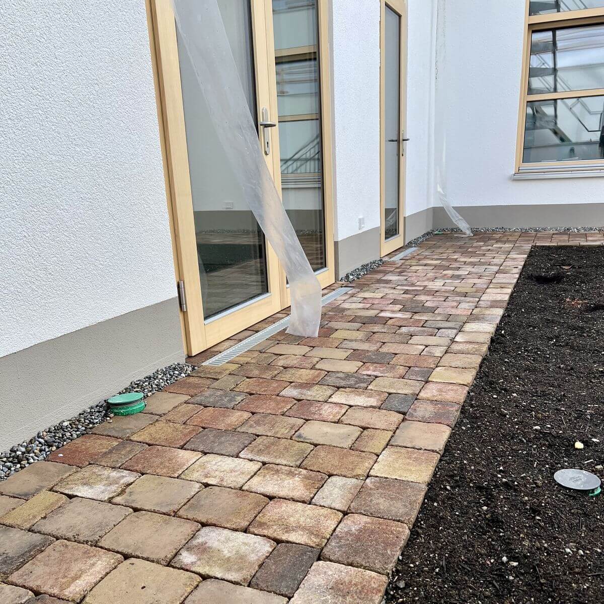 Verlegtes Rechteckpflaster in herbstbunten Farbtönen auf einer Terrasse direkt am Hauseingang.