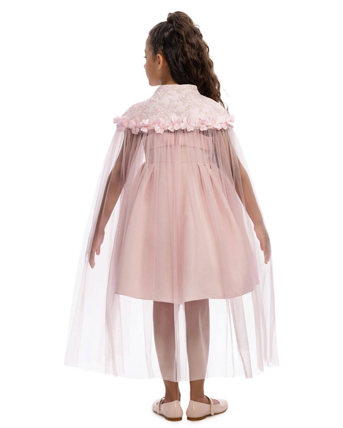 Young girl wearing a pink dress with a floral cape on a white background