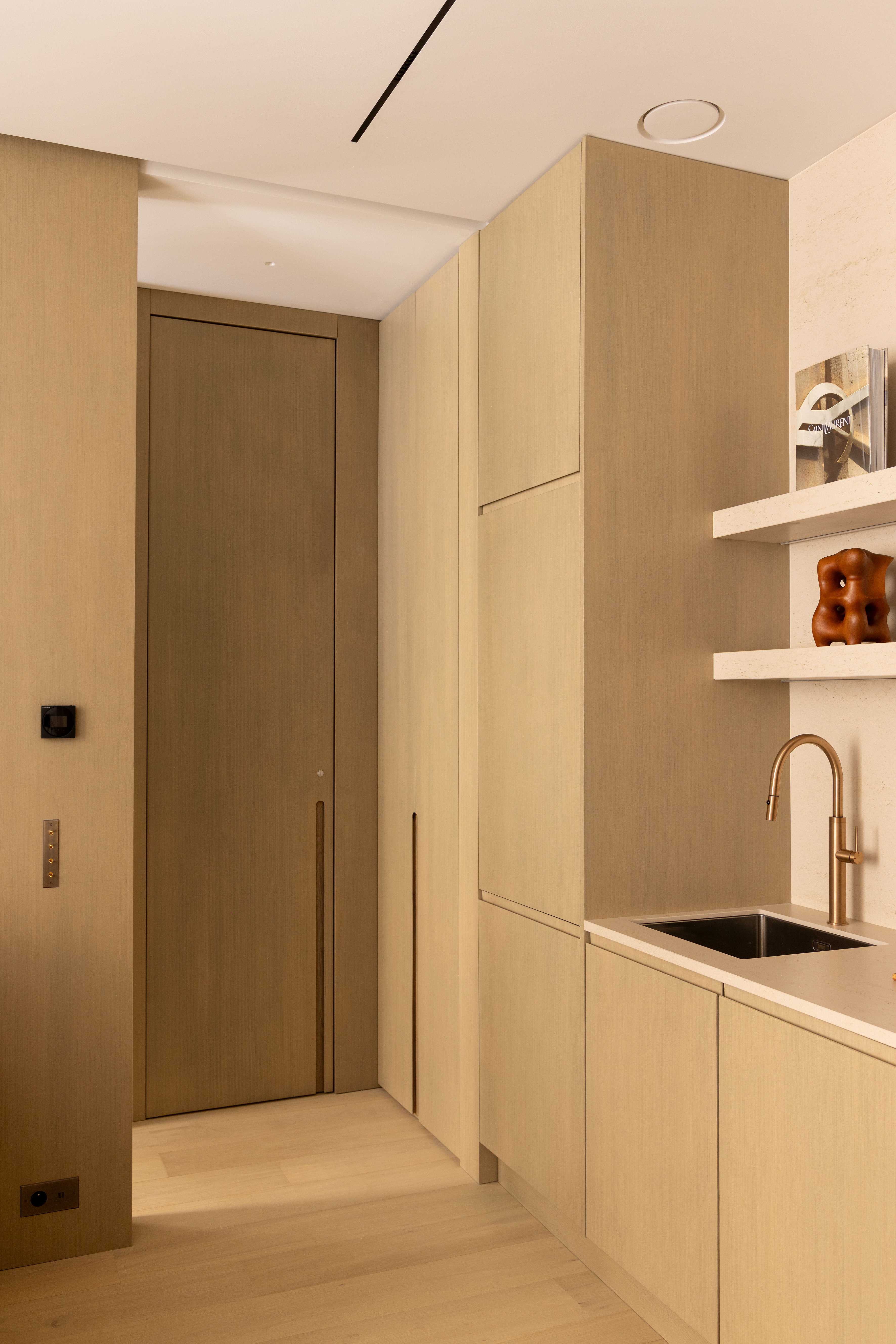 Entrée de l'appartement avec couloir en bois clair menant à la cuisine et la salle de bain
