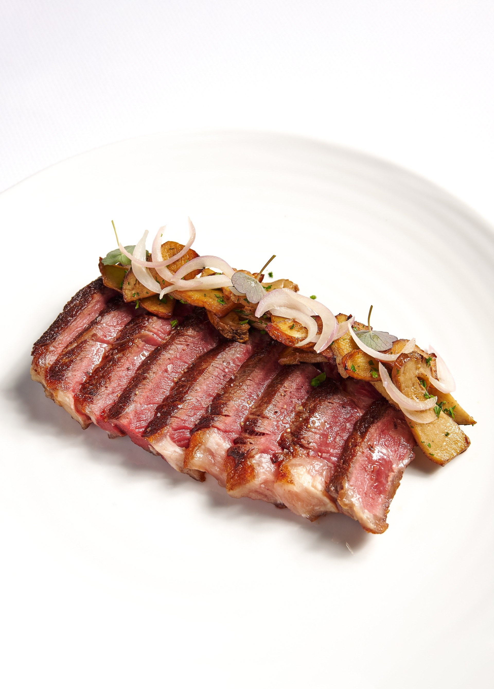 Perfectly grilled beef tagliata served sliced on a white plate