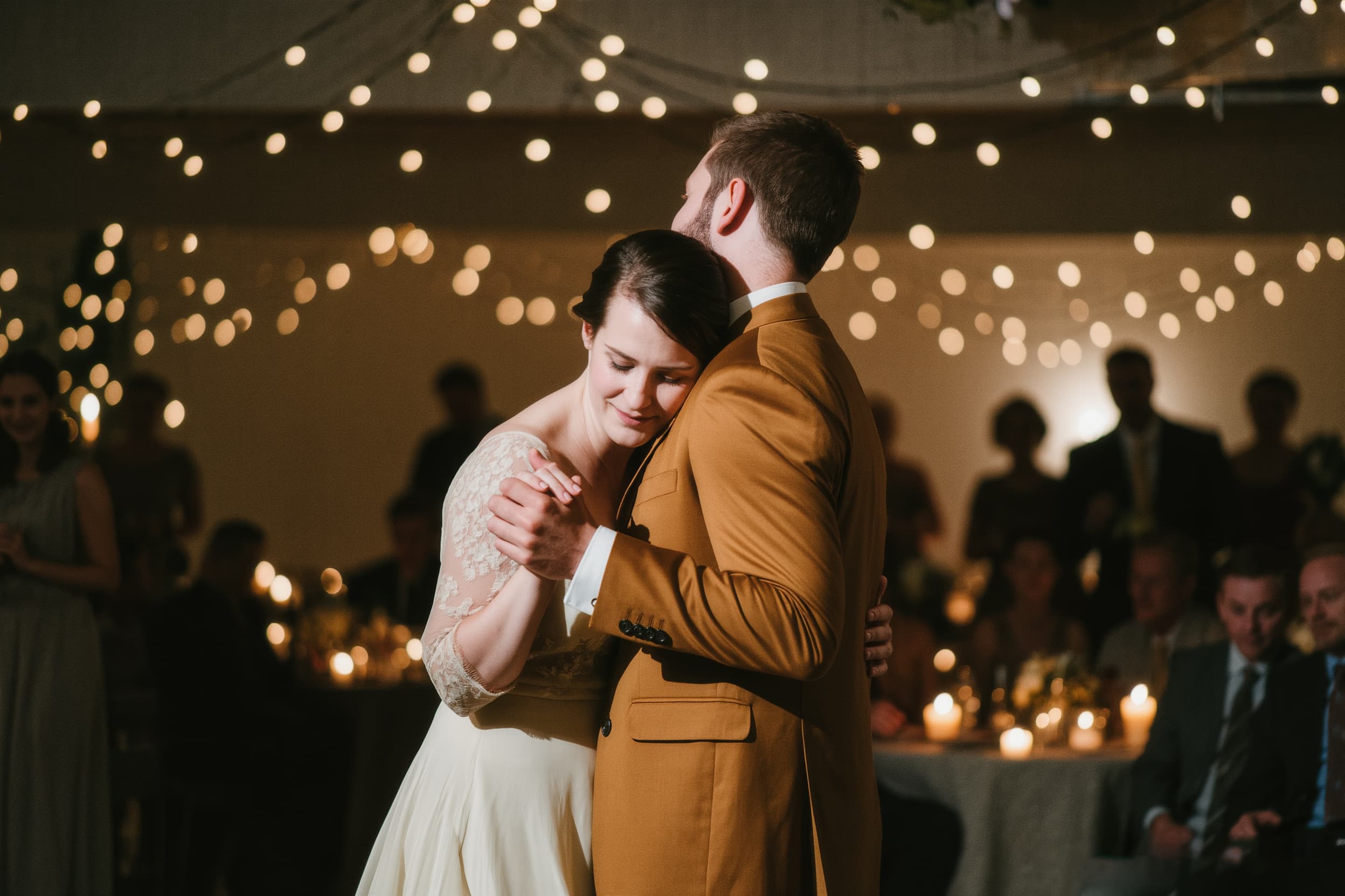 Wedding reception – couple dancing joyfully under string lights at evening celebration