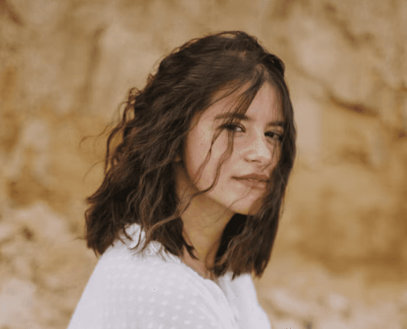 Jeune femme brune dehors devant un rocher jaune