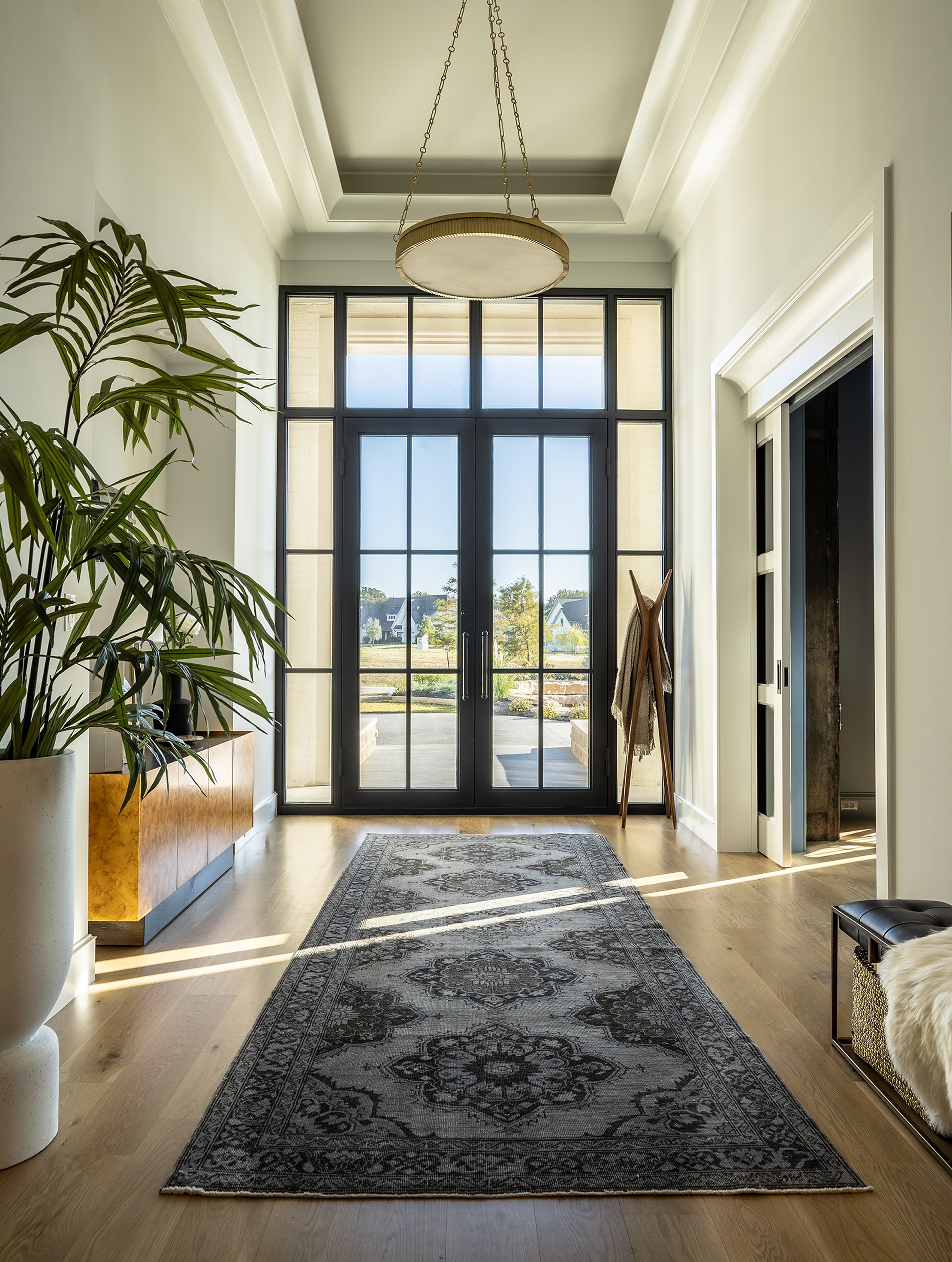 Fairview primary suite bedroom with dark walls, modern chandelier, tufted headboard, and seating area by large windows