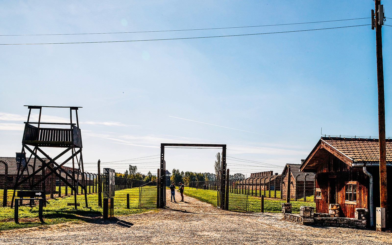 Auschwitz-Birkenau ingång med vakttorn och baracker under en klar himmel.