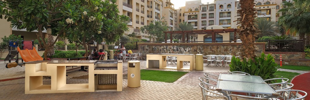 A residential area hosts The Square by OMNIYAT, featuring a park with a fountain and a playground for community enjoyment.