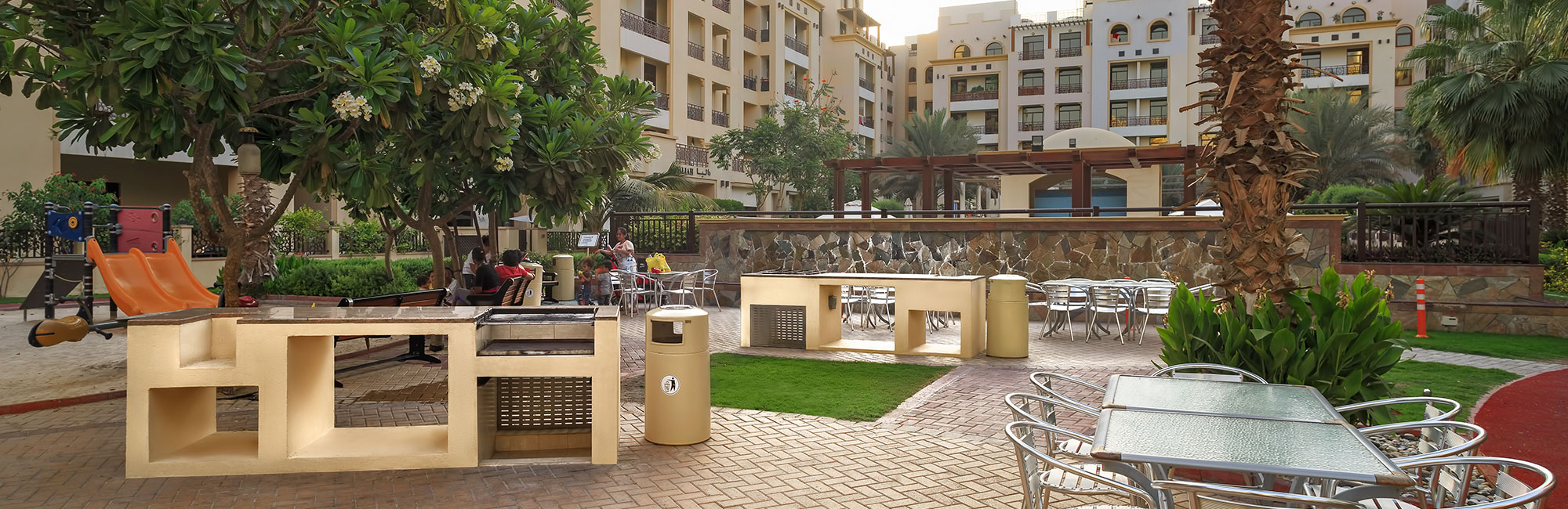 A residential area hosts The Square by OMNIYAT, featuring a park with a fountain and a playground for community enjoyment.