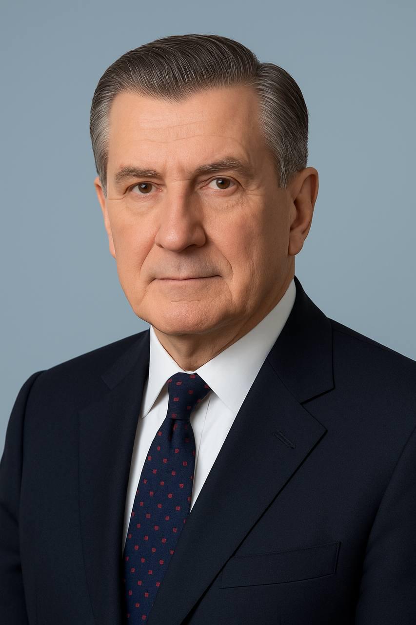 Portrait of a man with short dark hair and a trimmed beard, dressed in a dark shirt, on a simple background.