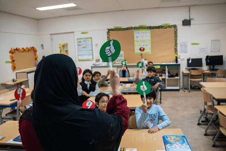 Leerkracht begeleidt leerling tijdens les op islamitische basisschool Al Qoeba in Den Haag