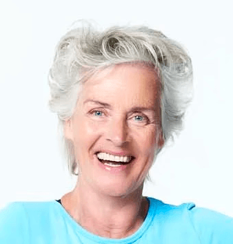 A smiling person with short blonde hair and glasses, standing against a light-colored background.