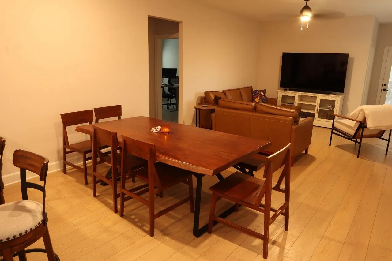 indoor-outdoor rain shower with natural stone and wooden slats, light filtering through tropical plants.