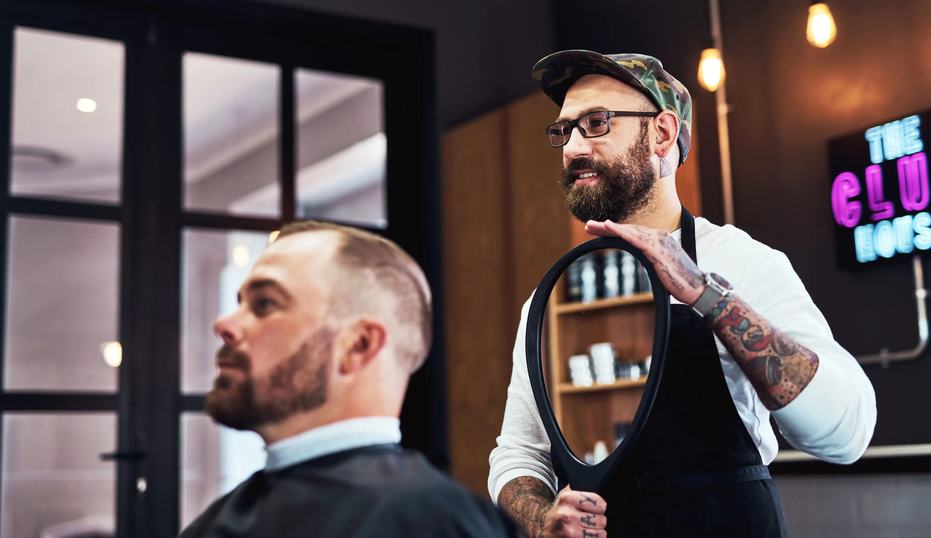 barbeiro cortando cabelo de cliente em barbearia moderna