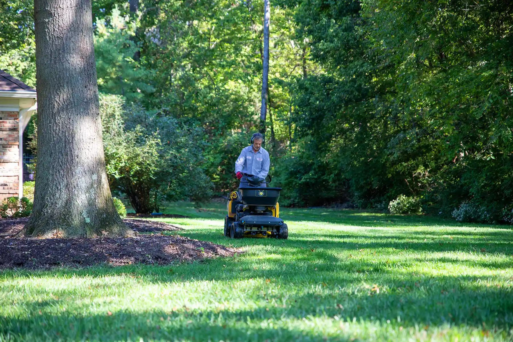 Image of a Pure Lawn employee riding a lawn machine