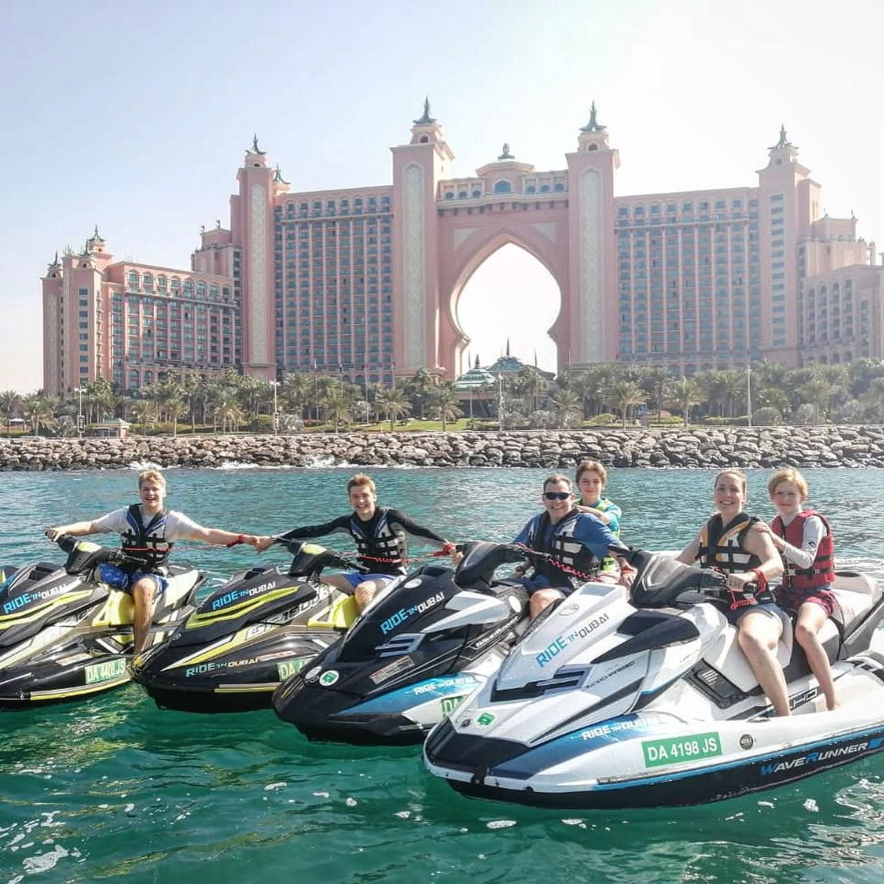 Group of people on their jet skis posing for a photo in front of the Palm Jumeirah.