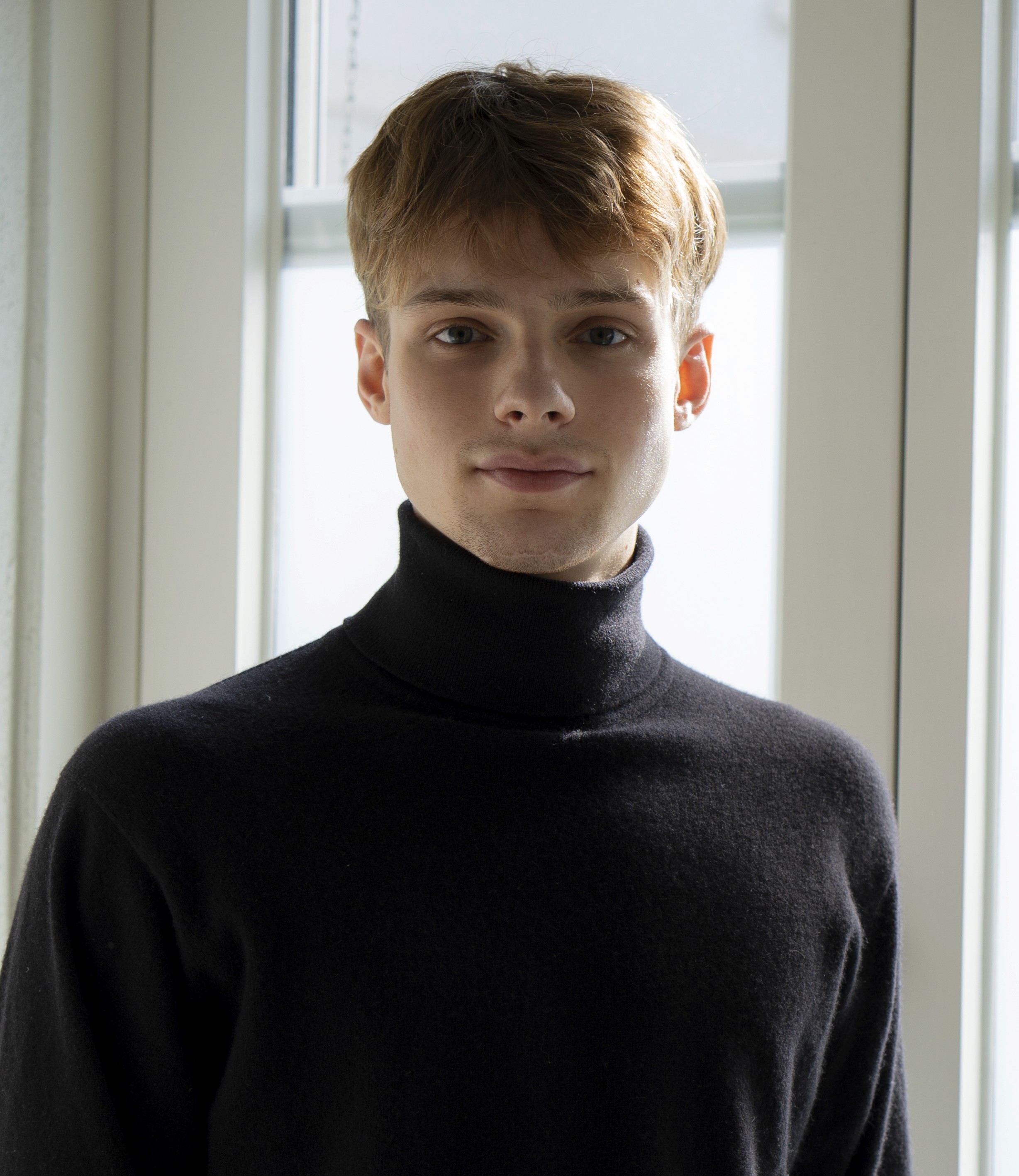 Portrait of a laughing person with curly hair wearing a white shirt