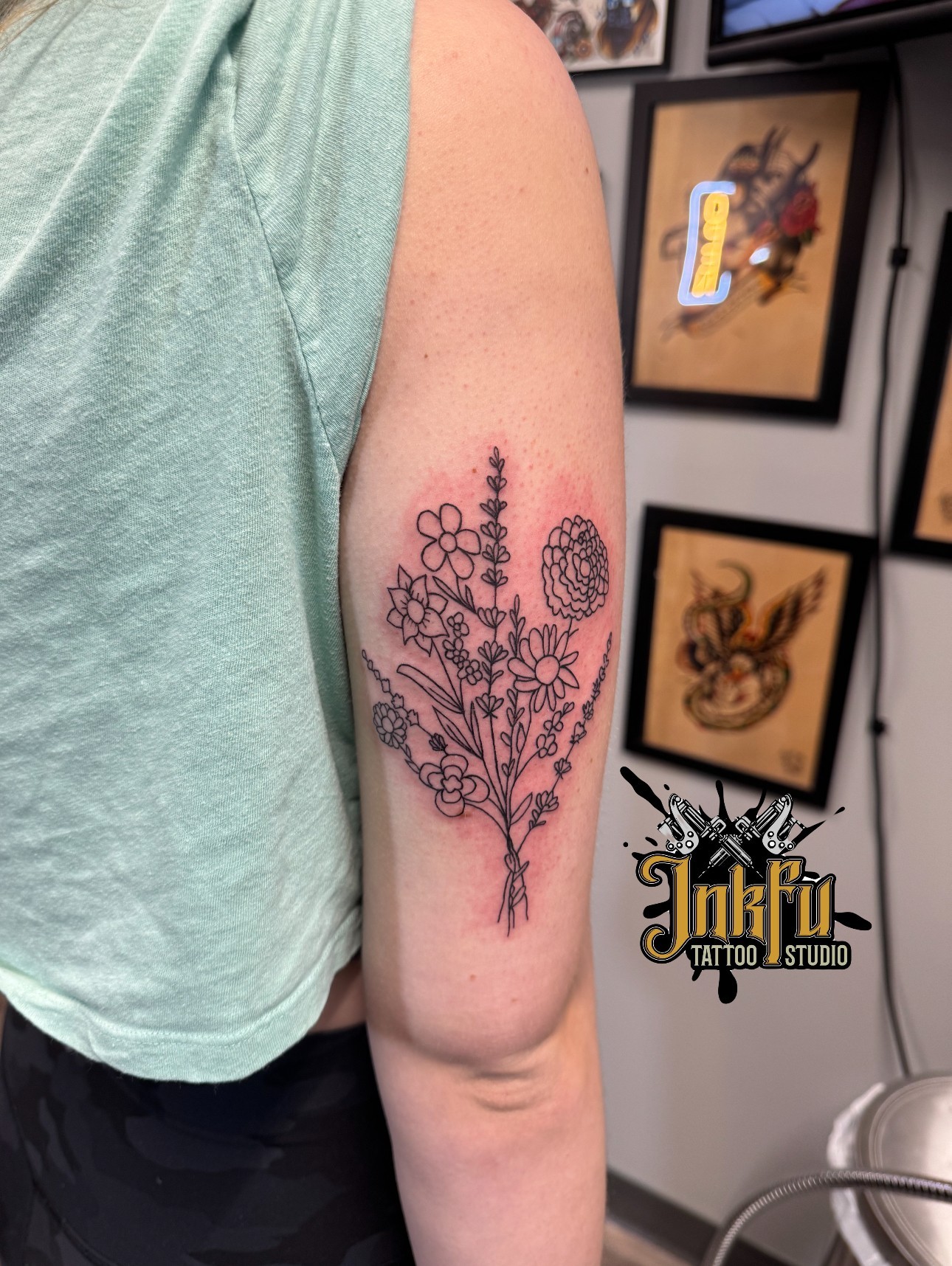 Fine line black outline floral tattoo on the upper arm, by Meer Rich