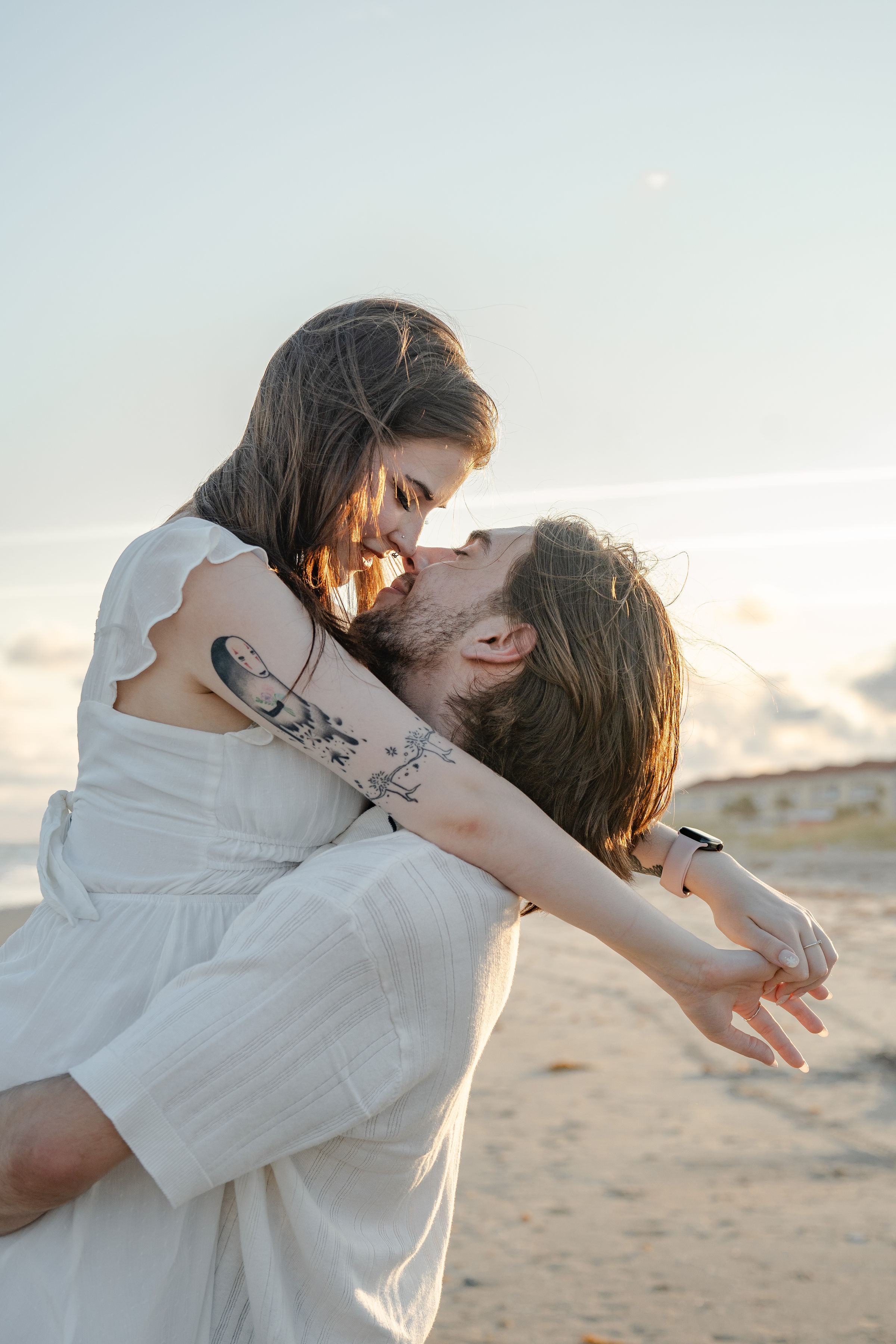 photo of a man picking up his wife during an intimate moment at sunset nearly kissing