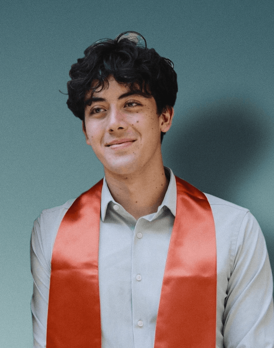 Smiling person with curly hair, wearing a black shirt, against a warm, dark background.