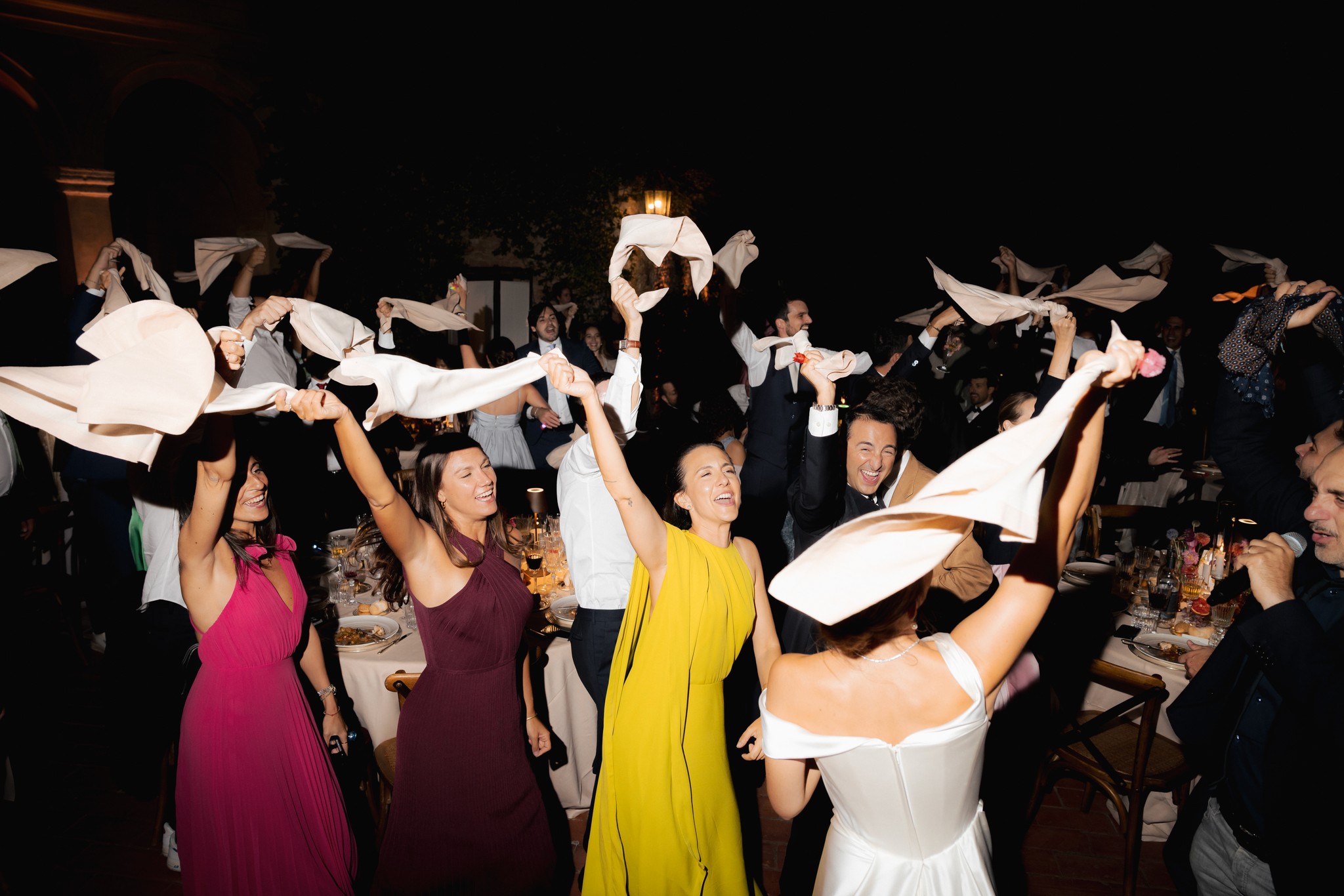 Ospiti lanciano tovaglioli bianchi in aria durante il ricevimento di matrimonio al Castello di Scipione, tra danze e festa